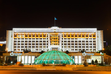 Almaty City Administration building illuminated at night, showcasing its grand architecture and vibrant atmosphere in the heart of the city.