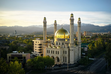 Scenic view of Almaty's golden-domed Central Mosque with the Tian Shan Mountains in the background, highlighting the charm of 'Almaty on a Budget' for cultural exploration.