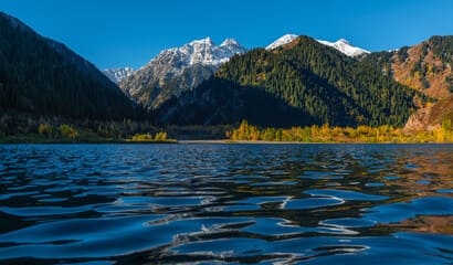 Stunning view of Jssyk Lake near Almaty, surrounded by rugged mountains and lush greenery, reflecting the tranquil beauty of this popular Almaty attraction.