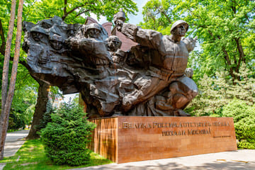 Monument to the Panfilov Heroes in Panfilov Park, Almaty, showcasing the bravery and sacrifice of the 28 Panfilov Guardsmen who defended Moscow during World War II. The monument is surrounded by lush greenery, reflecting the park's serene yet historically significant atmosphere."
