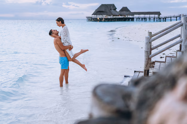 A romantic couple standing together by the ocean, enjoying a serene vacation with stunning turquoise waters and a clear sky in the background.